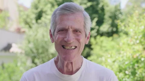 Elderly man smiling at camera in park, retirement serenity Stock Footage 285853085