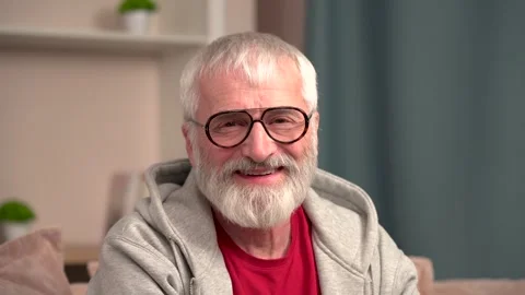 Elderly man smiling gently at the camera while sitting at home Stock Footage 303620904
