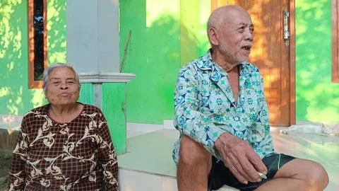 Elderly Man Smoking While Sitting at Home, Wife Reacts Stock Footage 316977929