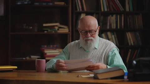 Elderly man sorting his mail in home library, checking paper utility bills Stock Footage 320671203