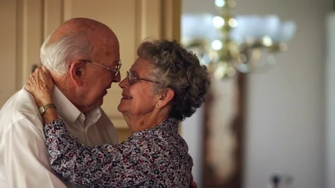 Elderly man speaks lovingly to his wife before giving her a romantic kiss. Stock Footage 88405495