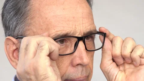 An elderly man squints, puts on his glasses Stock Footage 169648756