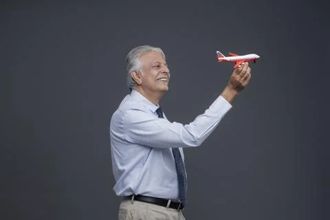 The Elderly Man Standing On The Right Side, Sttempting To Fly A Toy Plane  Stock Photos