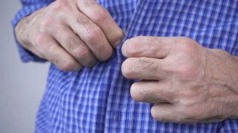 An elderly man struggles to button his clothes Stock Footage 170778520