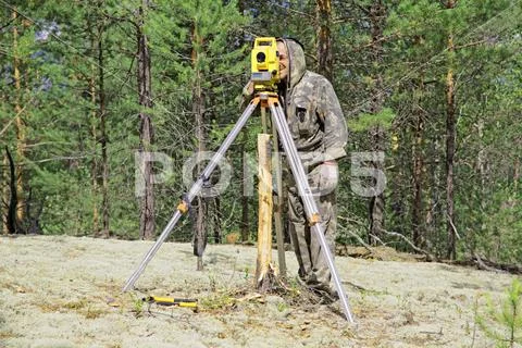 An elderly man is a surveyor at work in the overgrown taiga Stock Photos
