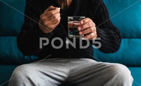 Elderly man takes his daily medication to combat his ailments. Stock Photos