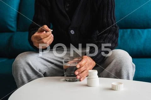 Elderly man takes his daily medication to combat his ailments. Stock Photos