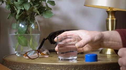 Elderly man taking a cod liver oil capsule with a glass of water. Video stock 107081319