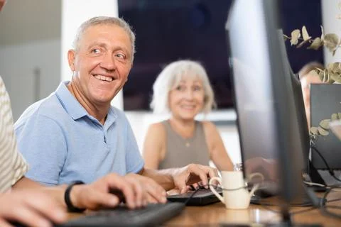 Elderly man taking computer lessons with group of elderly people in nursing home Stock Photos