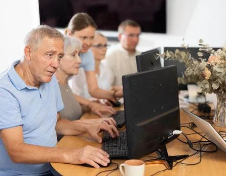 Elderly man taking computer lessons with group of elderly people in nursing home Stock Photos