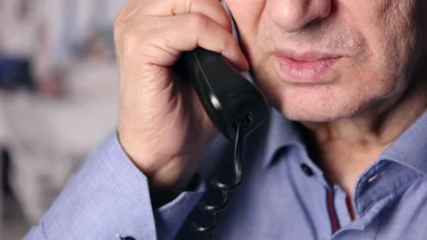 An Elderly Man Is Talking On A Black Wired Phone In The Office, Holding The Phon 스톡 동영상 147403131