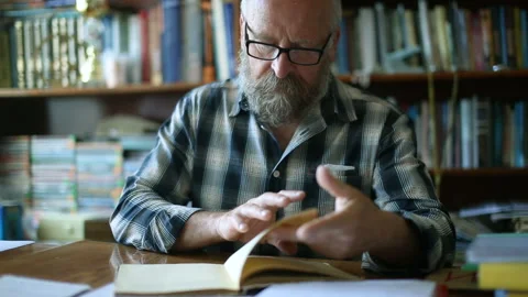 Elderly man thumbs a book Stock Footage 90949586