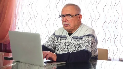 Elderly man types on laptop has conversations on phone Stock-Footage 107893276