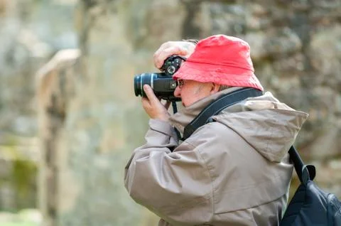 An elderly man uses a camera in ancient ruins Stock Photos