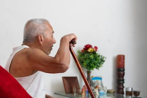 Elderly man using cane to stand up with effort showing mobility struggle an.. Stockfoto's