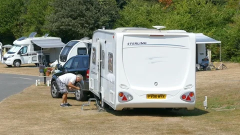 Elderly man using a crank handle to wind down a corner steady on his caravan. Stock-Footage 93076566