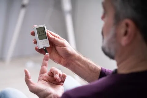 Elderly Man Using Glucometer To Check Blood Sugar Level Stock Photos