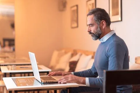 Elderly man using a laptop in a coffee shop Stock Photos
