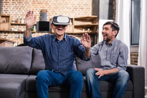 Elderly man using VR device with his son Stock Photos