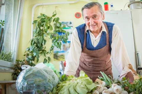 Elderly man with vegetables in kitchen Stock Photos