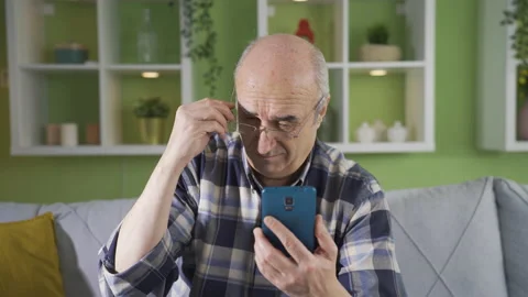 Elderly man with visual impairment has difficulty using the phone. Stock Footage 234142554