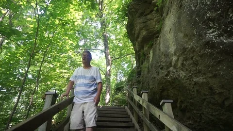 Elderly man walking down steps in a wooded area 動画素材 111425501