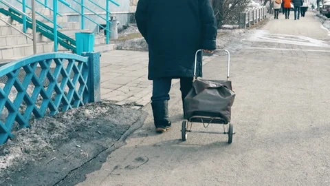 An elderly man walking down the street with a trolley bag Stock Footage 103647520