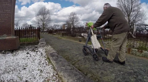 Elderly man with walking frame visits cemetery Stock Footage 55474546