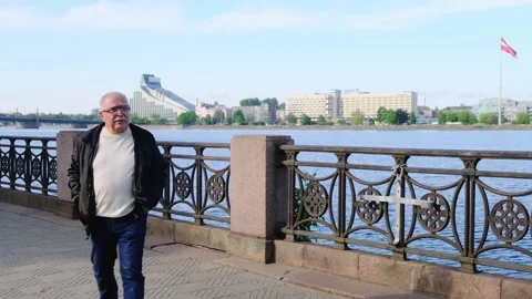 Elderly man walks to camera along renovated river embankment Stock Footage 139795091