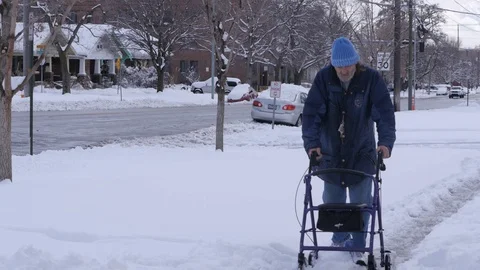 Elderly man walks down snow covered street with walker. Med Stock Footage 86750534