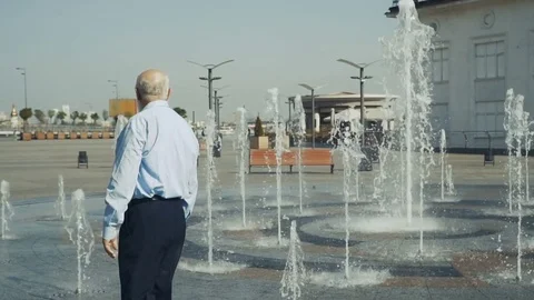 Elderly man walks under the fountain Stock Footage