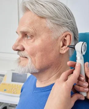 Elderly man while ear test with audiologist with otoscope at medical office.. Stock Photos