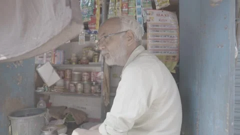 An elderly man who runs a corner store on the street in Mumbai, India Stock Footage 345389914