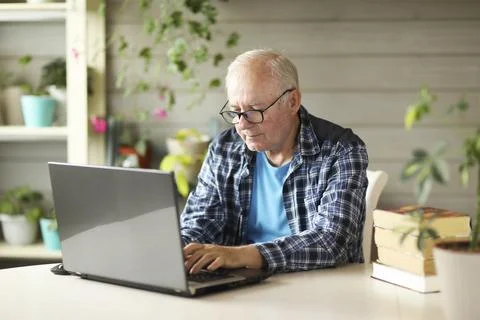 Elderly man working on computer while sitting at home Stock Photos