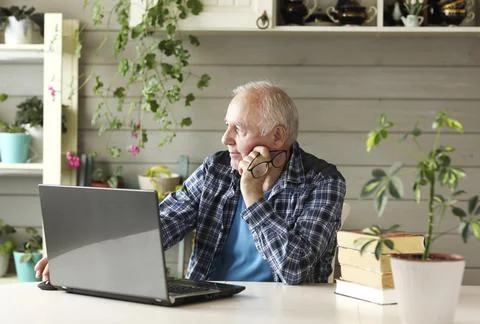 Elderly man working on computer while sitting at home Stock Photos