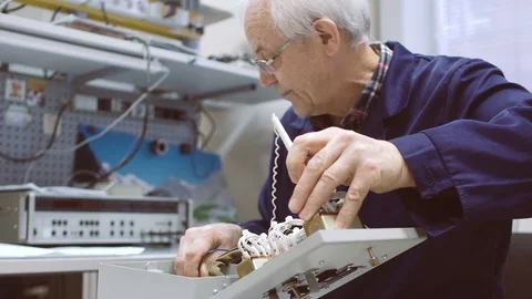 Elderly man working with electrical appliances. Tests the assembled circuit. Stock Footage 104286250