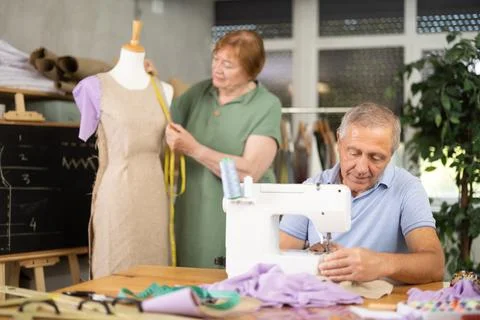Elderly man working at machine during group practical sewing course 库存照片