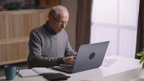 Elderly man is working remotely, sitting at his home office, counting by Video stock 153533806