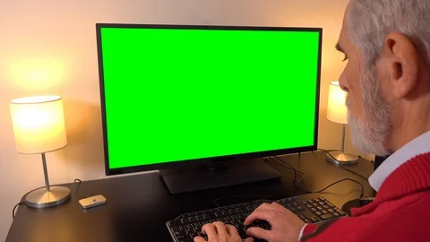 An elderly man works on a computer with a green screen in an apartment - closeup Vídeo Stock 115024207