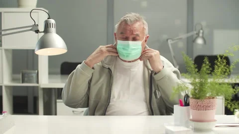 The elderly manager puts on a mask in fear and continues to talk in it Stock Footage 150336533