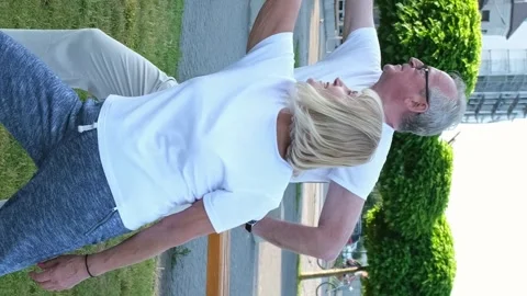 Elderly married couple is exercising doing yoga outdoors on the green lawn of Stock Footage 250111321