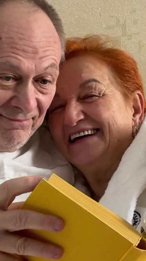 Elderly married couple sits on sofa in cozy living room. Couple hugs lovingly Stock Footage 323007729