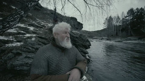 ​​Elderly Medieval Guard with Axe Watching Surroundings from Riverbank Stock Footage 295533713