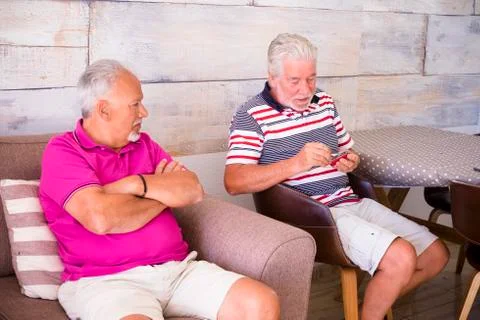 Elderly men sitting on the couch and chair talk Stock Photos