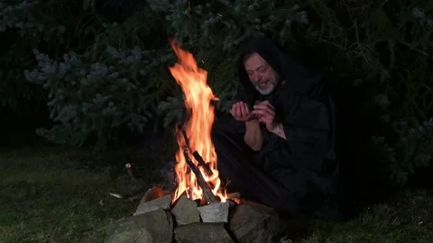 An elderly monk in a black robe counts money from his wallet while sitting by a  Stock Footage 303782892