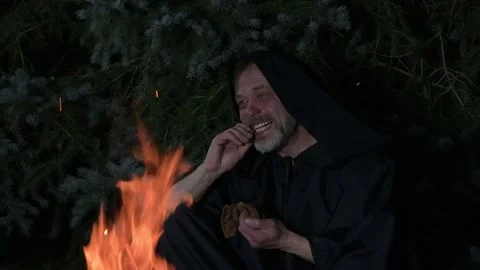 An elderly monk in a black robe counts money from his wallet while sitting by a  Stock Footage 303783685
