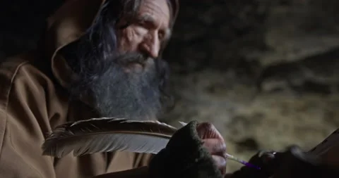 Elderly monk taking notes with quill in cave Stock Footage 169112164