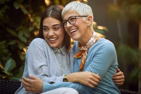Elderly mother and young adult daughter hugging each other Stock Photos