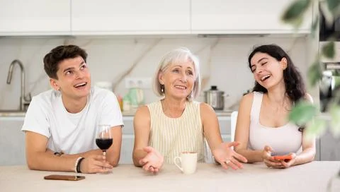 Elderly mother having good time with adult children drinking tea in live room Stock Photos
