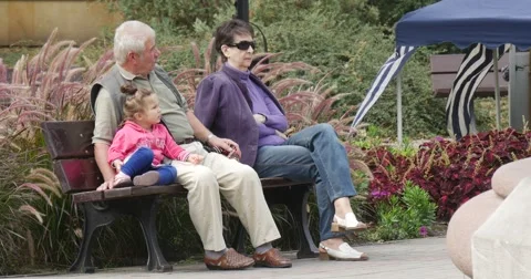 Elderly Pair Sit On The Wooden Bench With Little Girl They Discuss Something Stock Footage 54635689